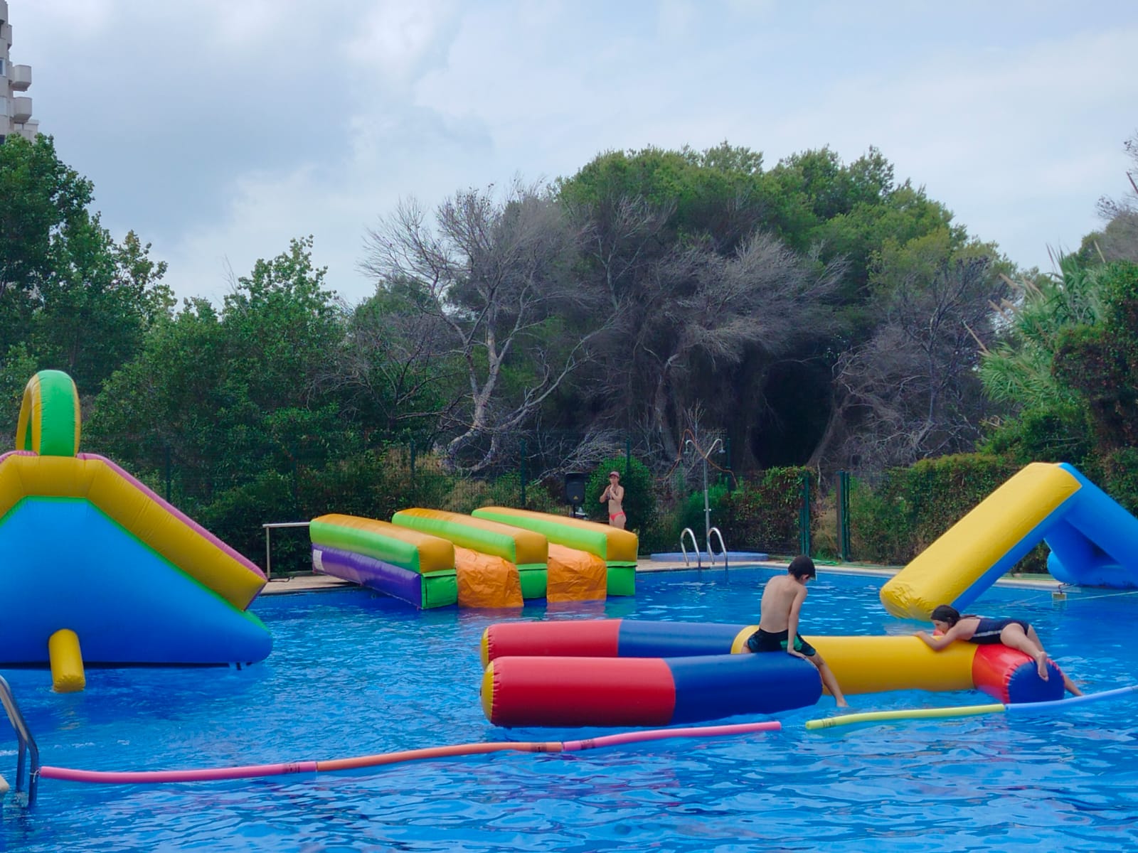 Parque acuático hinchable flotante con tobogán y obstáculos en piscina