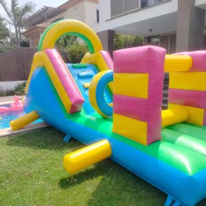 Parque acuático hinchable con tobogán y obstáculos junto a la piscina