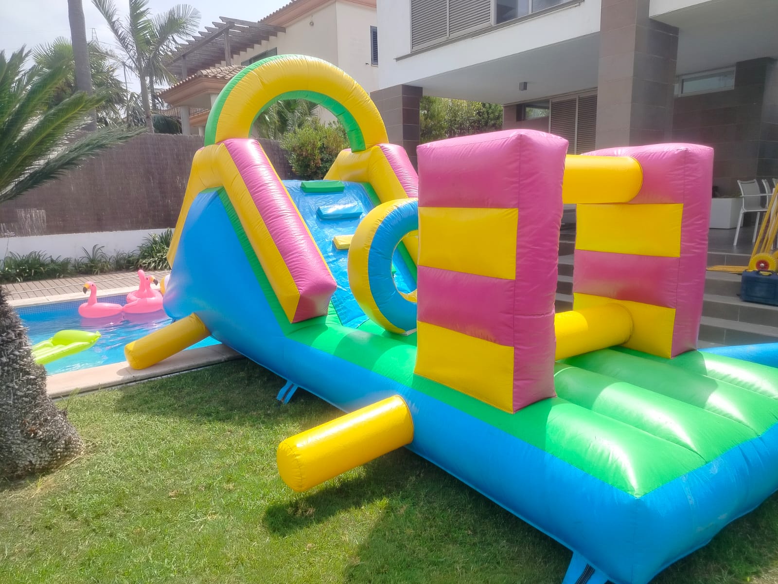 Parque acuático hinchable con tobogán y obstáculos junto a la piscina